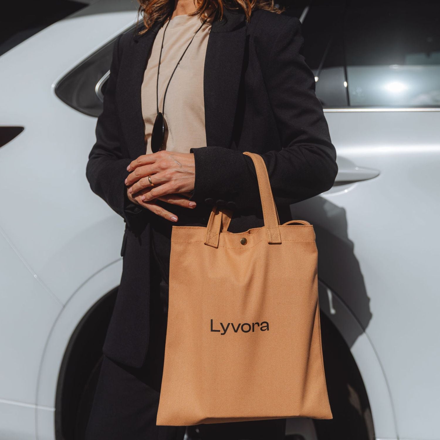 Woman holding Lyvora beige canvas tote bag in street style outfit
